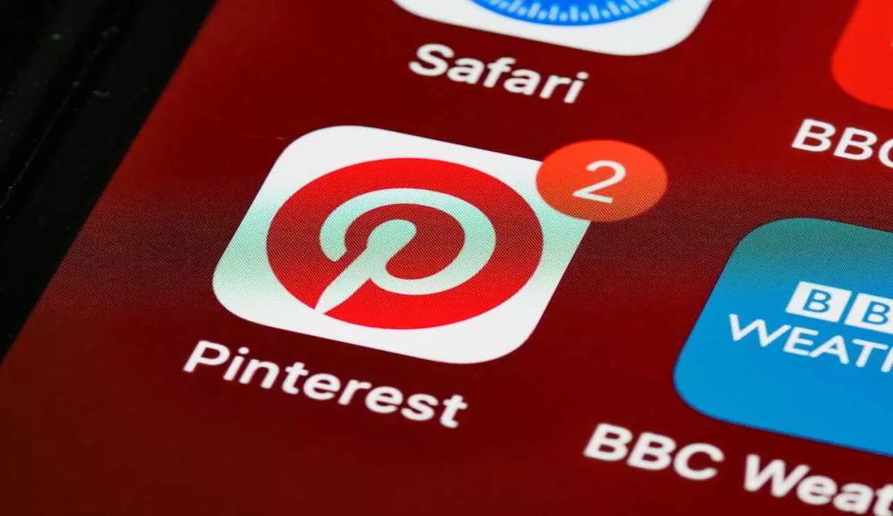 Aplikacja Pinterest na ekranie iPhone'a – ikona z logo Pinterest z powiadomieniem o 2 nowych aktywnościach; źródło inspiracji dla projektantów i twórców kreatywnych polecane przez Weronikę Wolską z Akademii Projektowania.