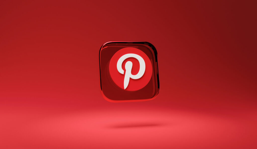 Trójwymiarowe logo aplikacji Pinterest na czerwonym tle – szklana ikona z białym symbolem Pinterest unosząca się w powietrzu; grafika ilustrująca artykuł o aplikacji Pinterest dla branży kreatywnej autorstwa Weroniki Wolskiej z Akademii Projektowania.