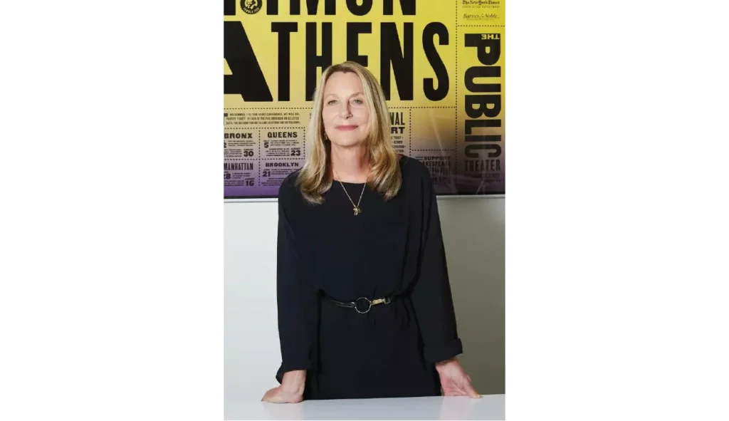 Paula Scher, amerykańska projektantka graficzna XX i XXI wieku, na tle własnego plakatu dla The Public Theater. Zagraniczne projektantki graficzne XX i XXI wieku. Kogo warto znać?